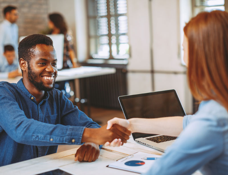 Man and woman shaking hands across a desk