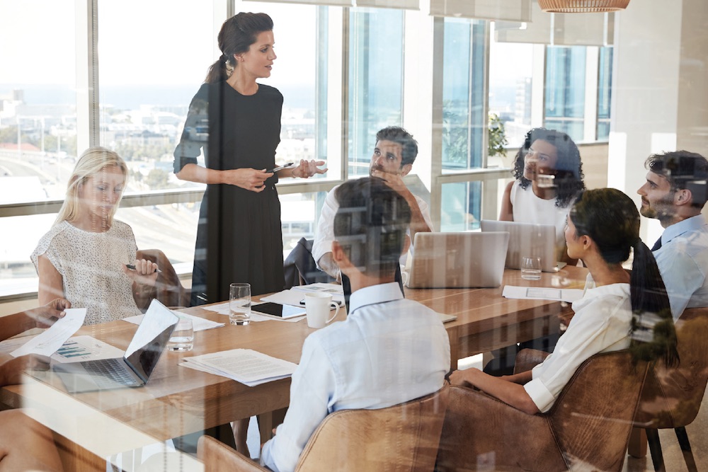 glass conference room with coworkers sitting around a table