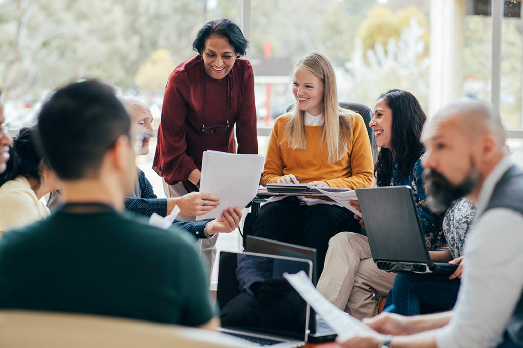 Group of people with laptops sitting in a circle